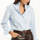 Tyler Böe Natalie Sateen Shirt in light blue, front view, tucked into brown faux-leather pants