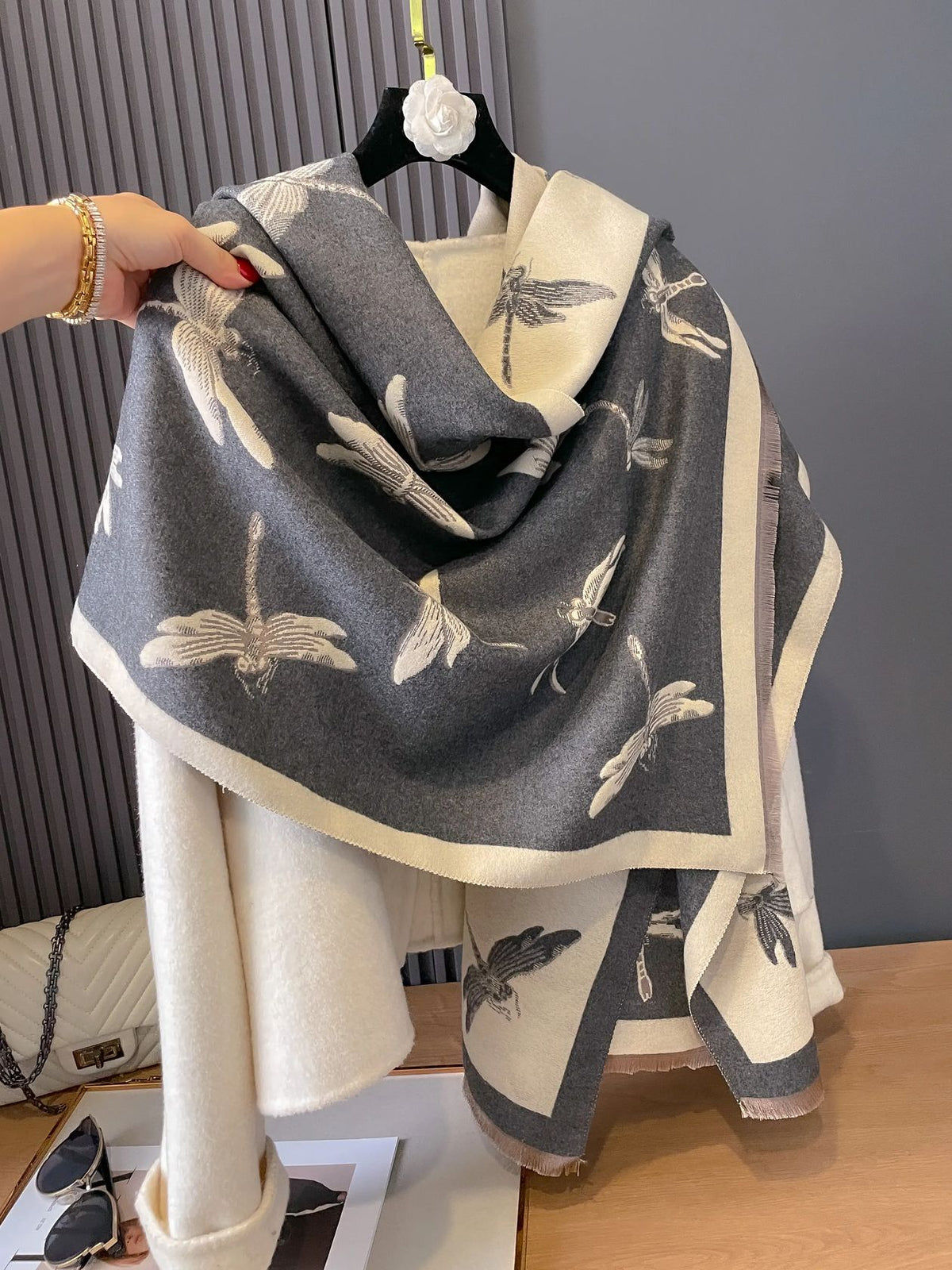 Winding River Dragonflies Reversible Wrap/Scarf in dove gray and ivory with dragonfly print and fringed ends, shown on a hanger