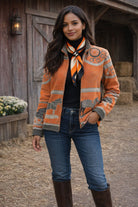 Winding River Gallop Zipper Sweater in burnt orange with gray galloping horse motifs, worn with jeans and brown riding boots