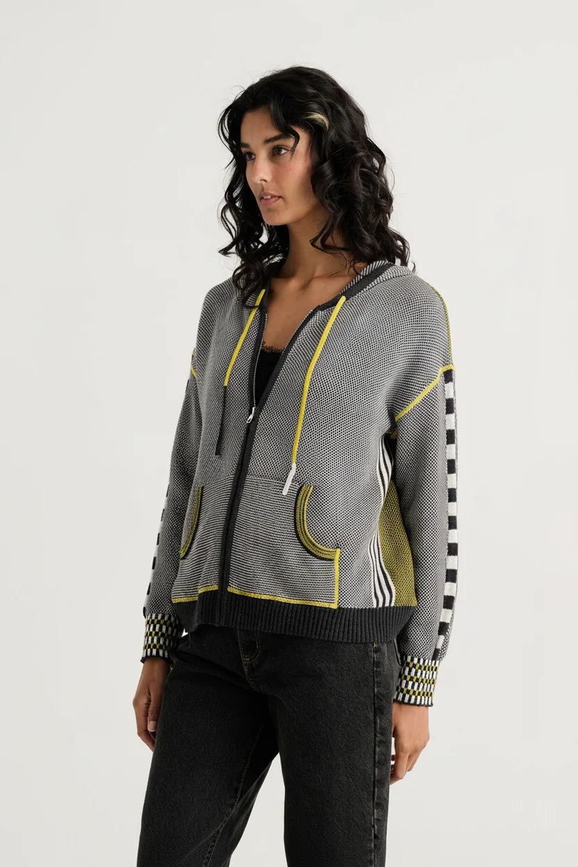 Zaket & Plover Birdseye Hoodie, woman modeling a gray zip-up hoodie with yellow piping, striped sleeve panels, and checkered cuffs, paired with black jeans