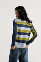Back view of the Zaket & Plover Color Theory V sweater showing navy, soft blue and olive green stripes, styled with blue jeans