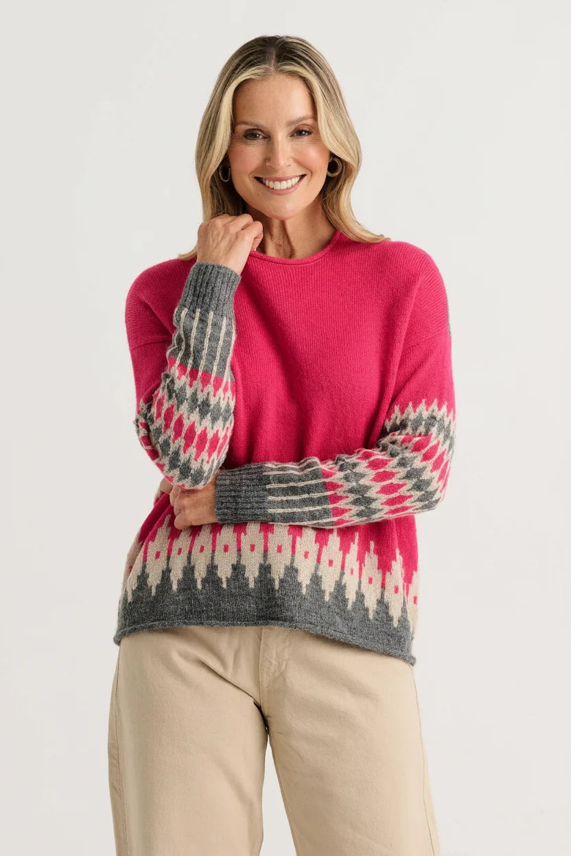 Woman wearing the Zaket & Plover Jacquard Sweater in Fuchsia, a relaxed crew neck knit with a grey and cream jacquard hem and sleeves, styled with beige trousers
