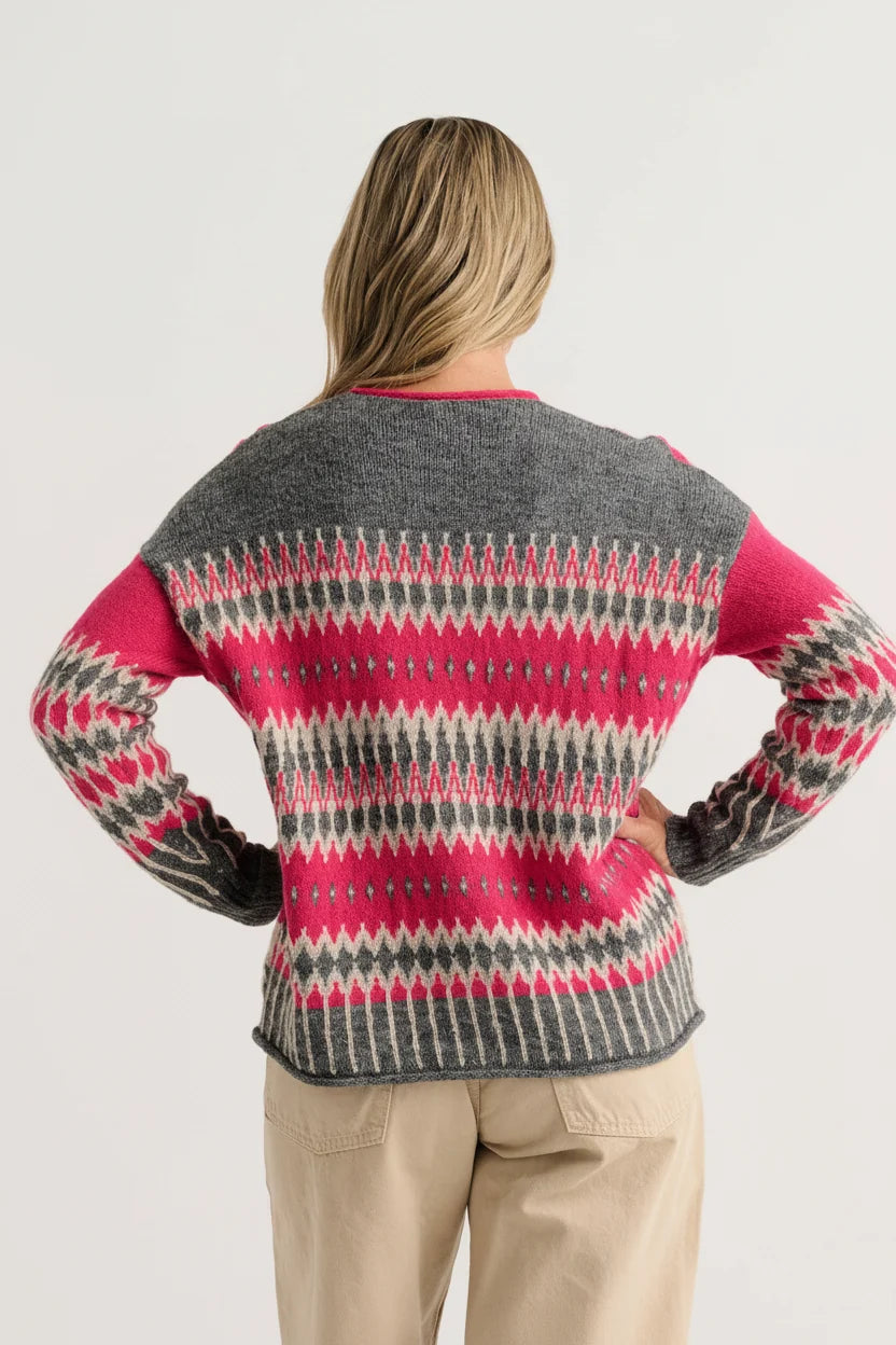 Back view of the Zaket & Plover Jacquard Sweater in a grey and fuchsia all-over jacquard knit, styled with beige trousers
